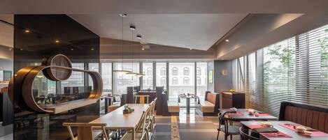 Een modern restaurant met een lange gedeelde tafel, afzonderlijke zitjes en een bar.