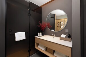 Un baño moderno con una puerta oscura, un lavabo blanco, un espejo y un perchero para toallas.