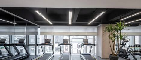 A modern gym with treadmills, a stationary bike, and a weight bench.