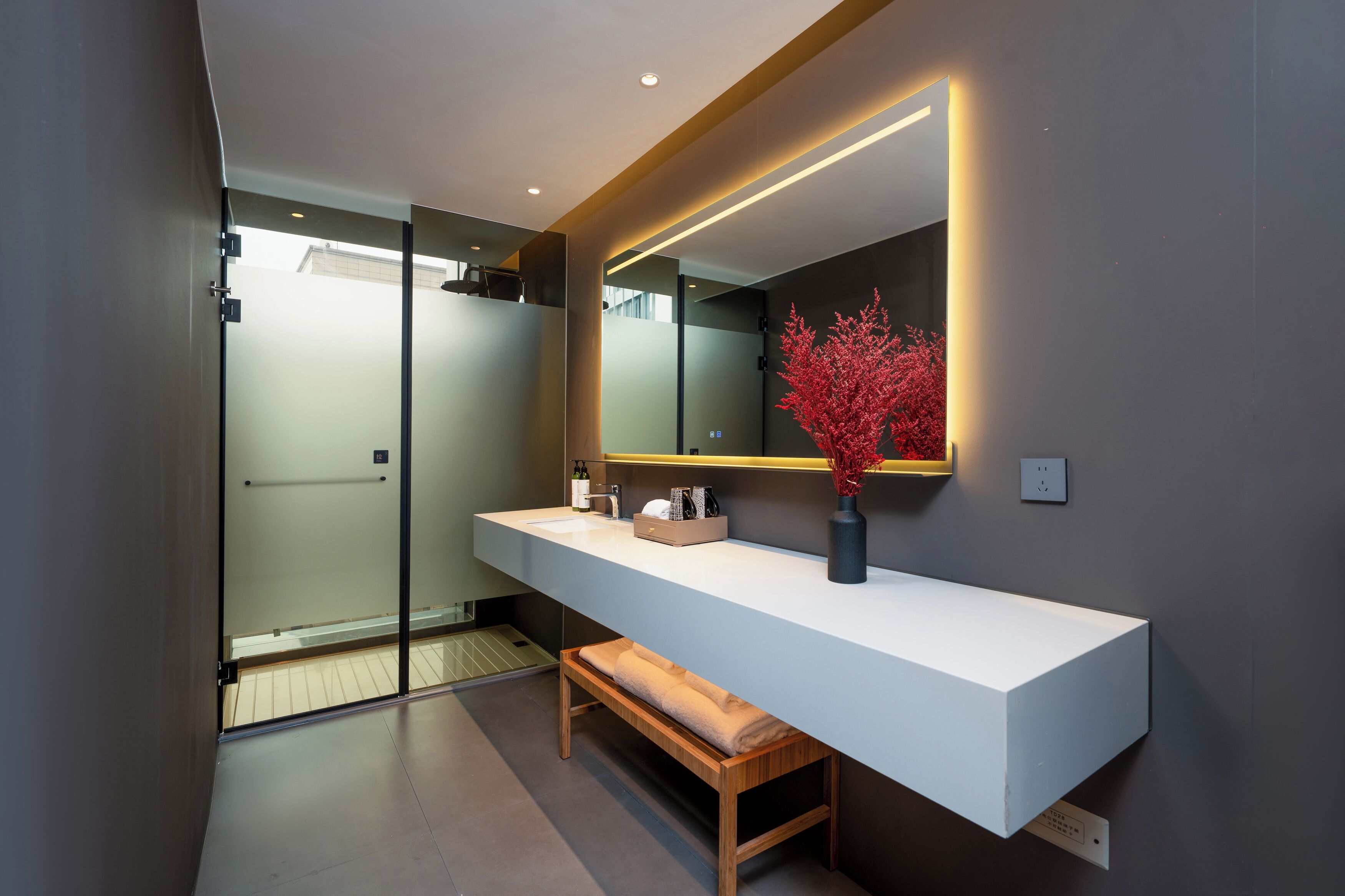 Un baño moderno con un tocador blanco, un espejo grande y un banco.