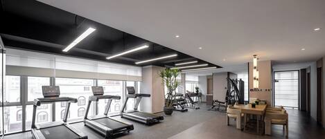 A modern gym with treadmills, weight machines, and a dining area.