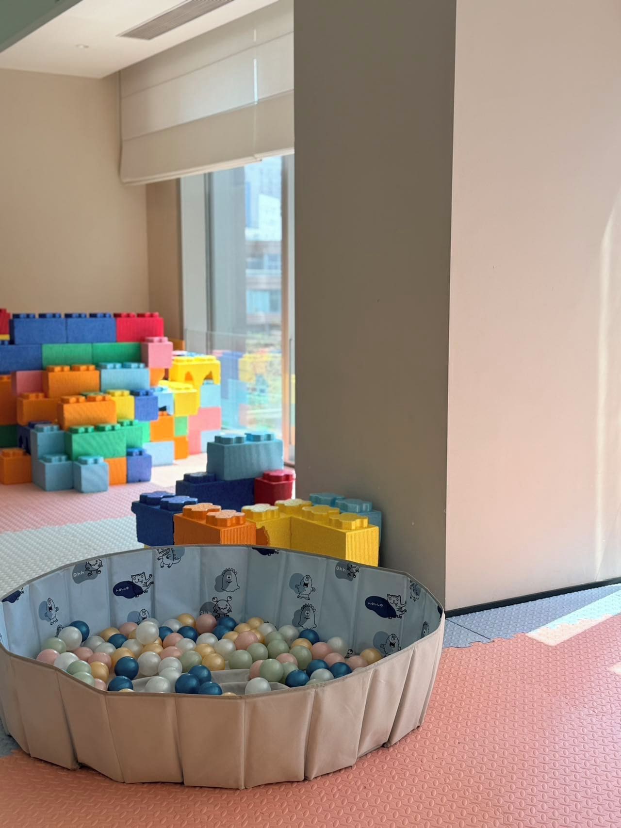 Una habitación con un área de juegos que incluye bloques de construcción coloridos y una piscina de pelotas.