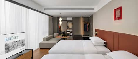 Habitación de hotel con dos camas, televisión, sofá, mesa de comedor y vistas a la ciudad.