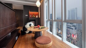A modern dining area with a round table, a sofa, and a view of a cityscape through large windows. - SSAW Garden Hotel Chengdu - Chunxi Road Taikoo Li Branch (Chengdu)