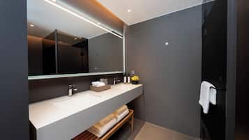 Une salle de bain moderne avec un grand miroir, deux lavabos, un banc et un porte-serviettes.