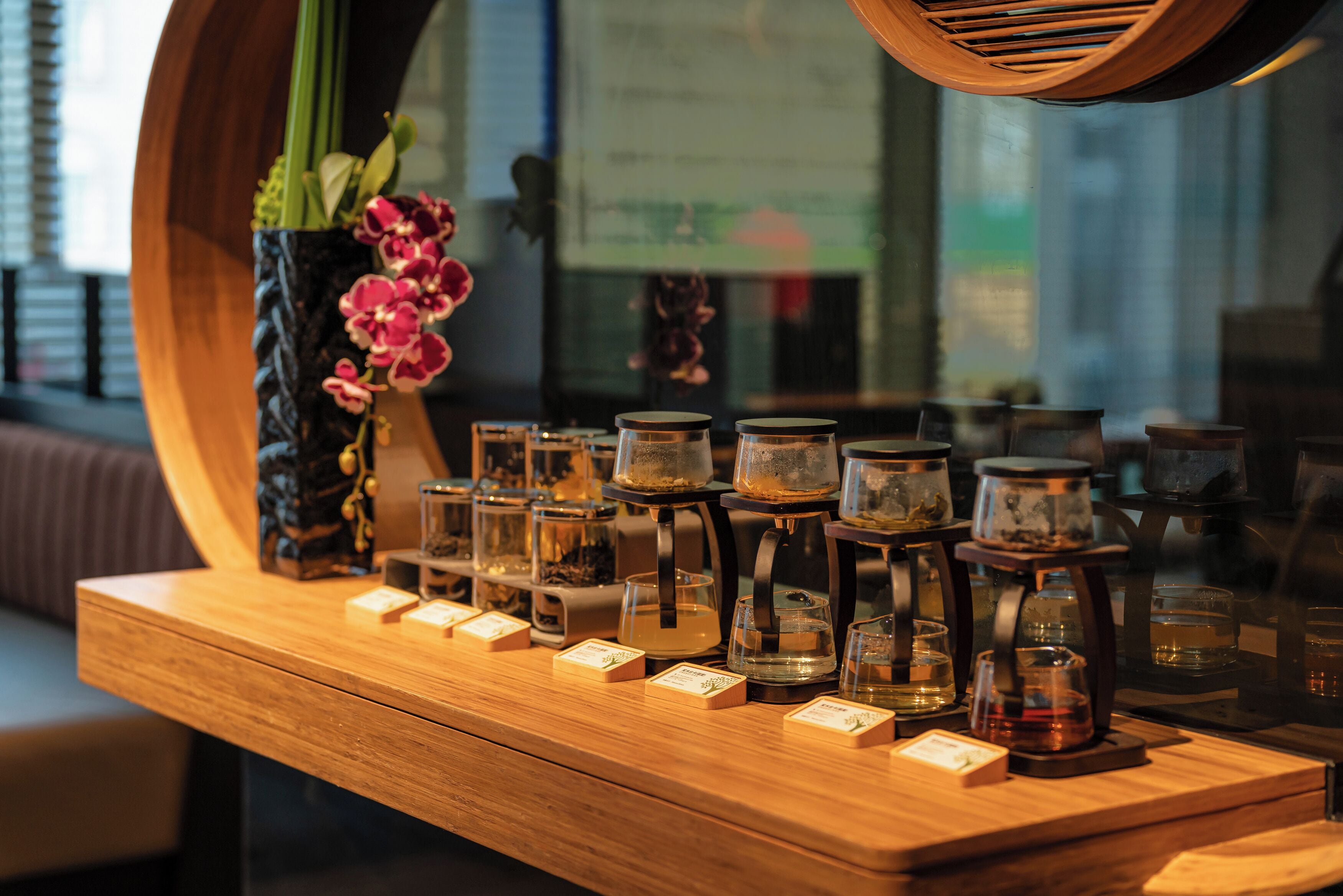 A wooden counter with jars of tea and a vase of flowers.