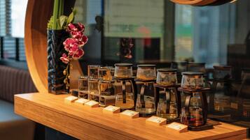 A wooden counter with jars of tea and a vase of flowers.