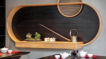 A wall-mounted wooden shelf with a blackboard, a teapot, and a small potted plant.