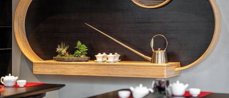 A wall-mounted wooden shelf with a blackboard, a teapot, and a small potted plant.