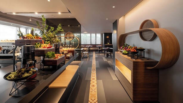 A modern restaurant with a long counter, a variety of fruits and vegetables displayed, and a seating area with tables and chairs. - SSAW Garden Hotel Chengdu - Chunxi Road Taikoo Li Branch (Chengdu)