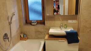 Un bagno con vasca, lavandino, specchio e finestra.