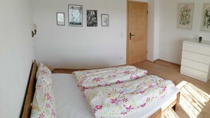 Una camera da letto con un letto di legno, una cassettiera bianca e opere d'arte floreali alle pareti.