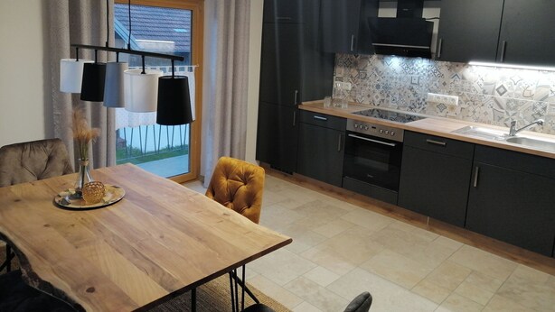Una cucina moderna con mobili scuri, un piano di lavoro in legno e una parete di fondo decorata.