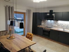 A modern kitchen with dark cabinets, a wooden countertop, and a built-in oven. - Vacation apartment with 2 bedrooms, 85 sqm (Traunstein)