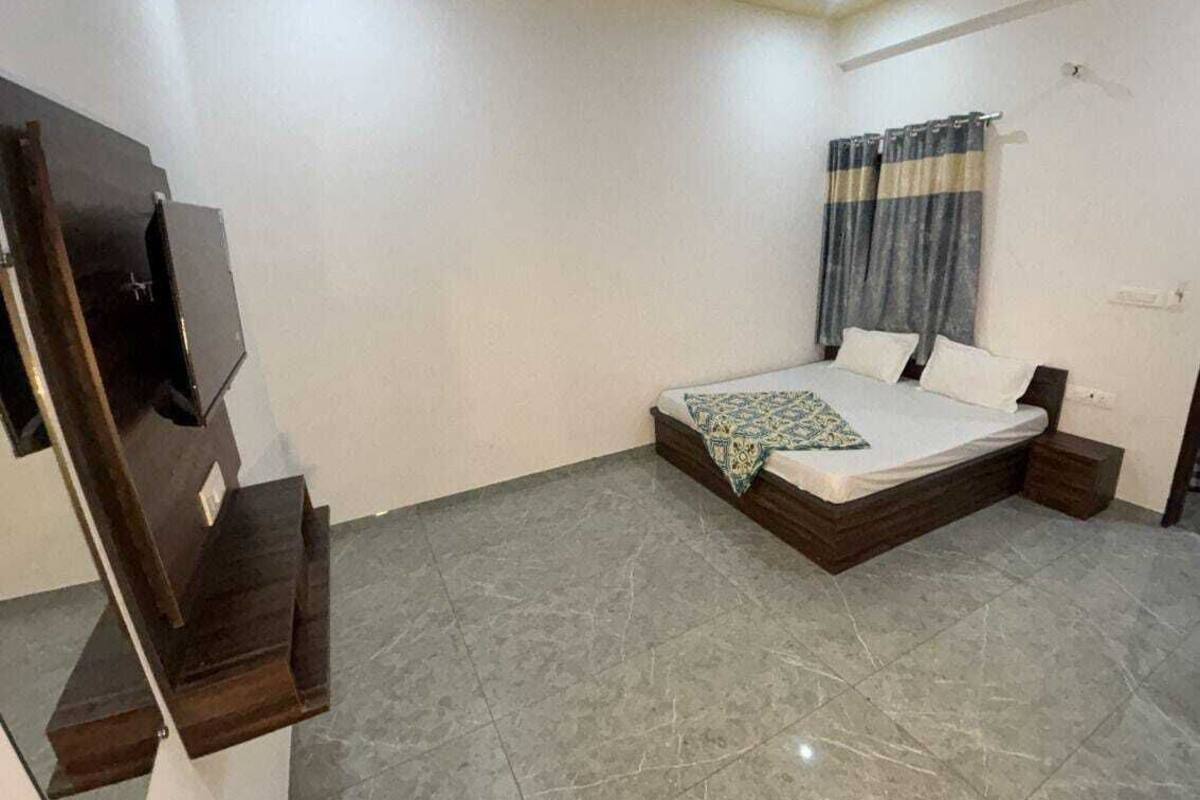 A bedroom with a bed, a TV, and a window with curtains.