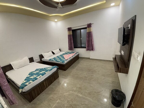Habitación de hotel con dos camas, un televisor montado en la pared y una ventana con cortinas.