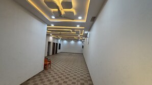 A spacious hallway with a checkered floor, recessed lighting, and a ceiling fan. - Shree Shyam Kiran Palace (Danta Ramgarh)