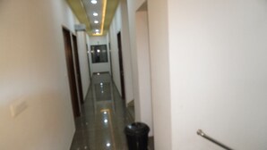 A narrow, well-lit hallway with a trash bin and a door on the right. - Shree Shyam Kiran Palace (Danta Ramgarh)