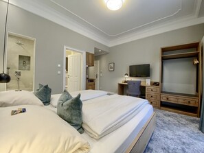 Habitación de hotel con dos camas, un escritorio con silla, televisión y armario.