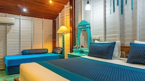 Une chambre d’hôtel avec un grand lit, un canapé bleu, un miroir et une lampe.