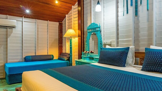Una habitación de hotel con una cama grande, un sofá azul, un espejo y una lámpara.