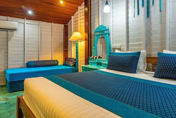 Una habitación de hotel con una cama grande, un sofá azul, un espejo y una lámpara.