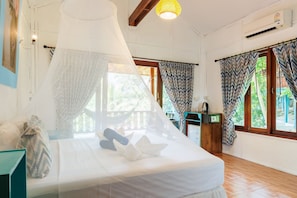 Quarto com cama, mesa de cabeceira, rádio e vista para o verde lá fora.