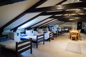 A dormitory-style room with bunk beds, a dining table, and chairs. - Stf Af Chapman Hostel (Stockholm)
