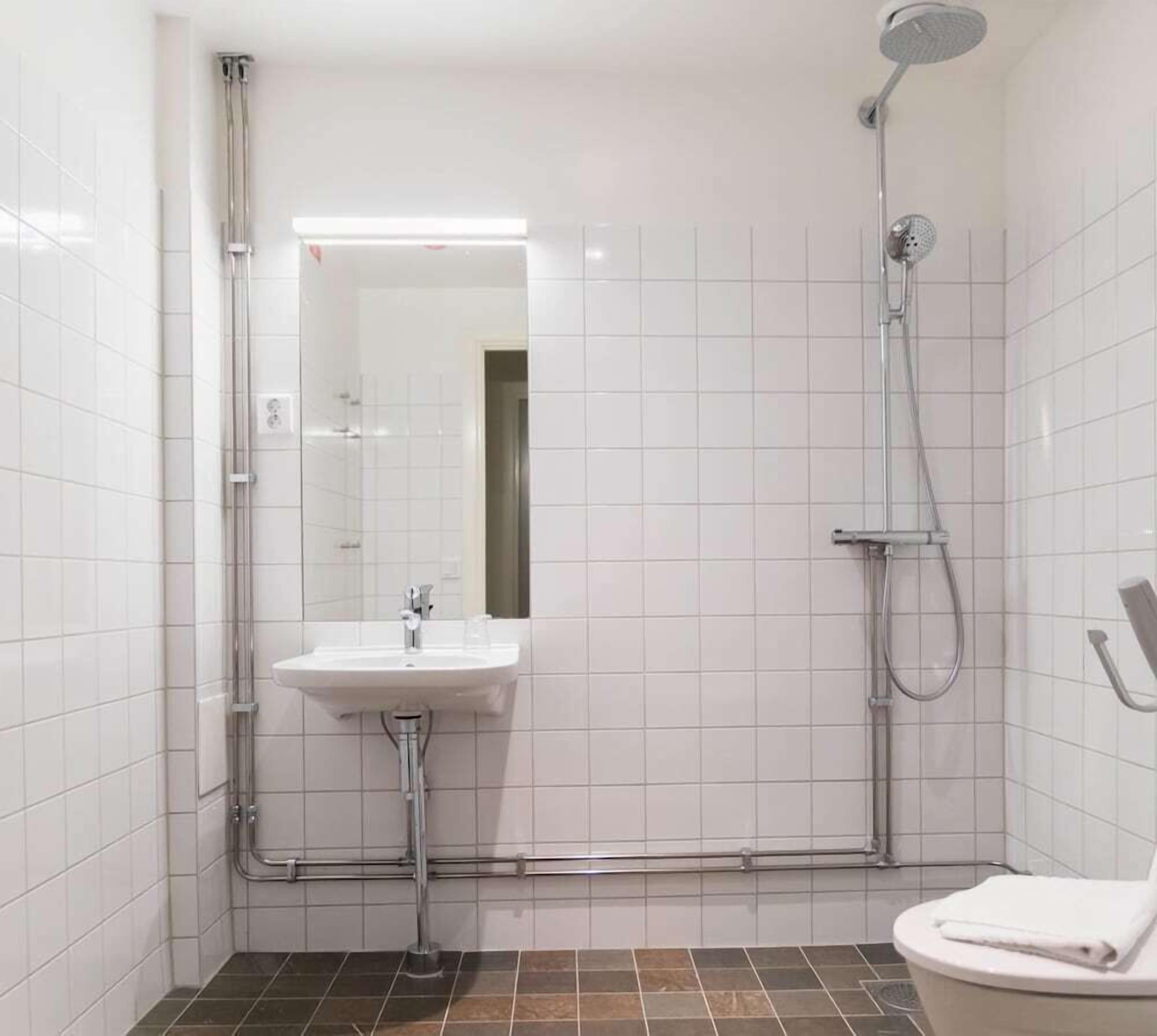 Ein modernes Badezimmer mit Waschbecken, Spiegel, Dusche und Toilette.