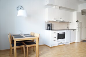 Eine moderne Küche mit weißen Schränken, einer Kaffeemaschine und einem Esstisch mit Stühlen.