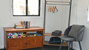 Una habitación con escritorio de madera, una silla, un ventanal y un perchero.