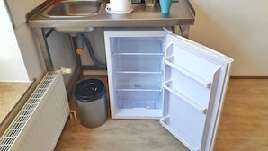 A compact kitchen with a built-in refrigerator, a sink, and a trash bin. - B & L Hostel (Bremen)