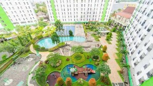 A residential complex with a central swimming pool, landscaped gardens, and a children's play area. - Japlen Room (South Tangerang)
