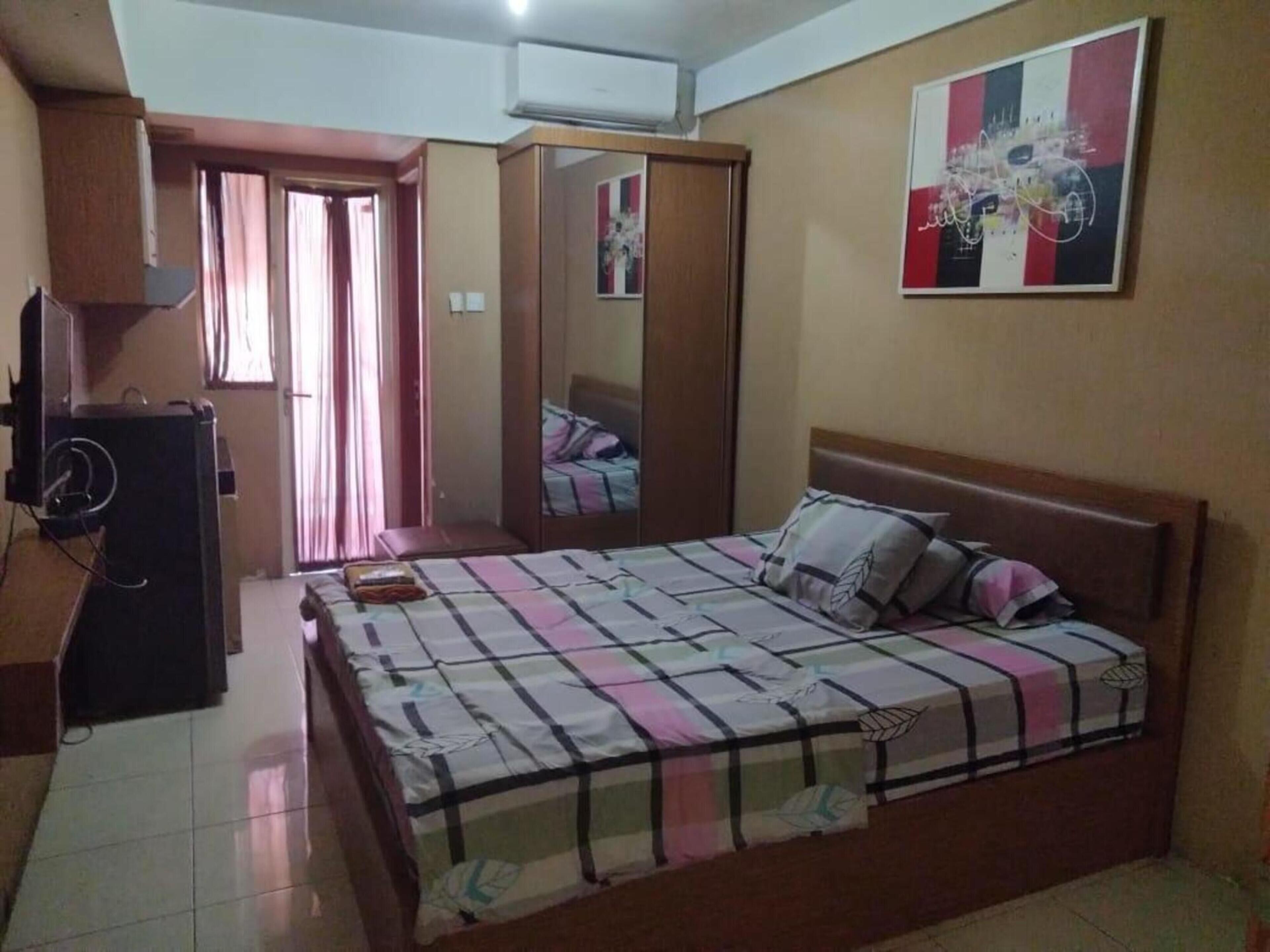 A bedroom with a bed, a wardrobe, a desk, and a mirror.