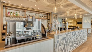 Un espace bar équipé d’une machine à café, d’étagères remplies de bouteilles et de verres.