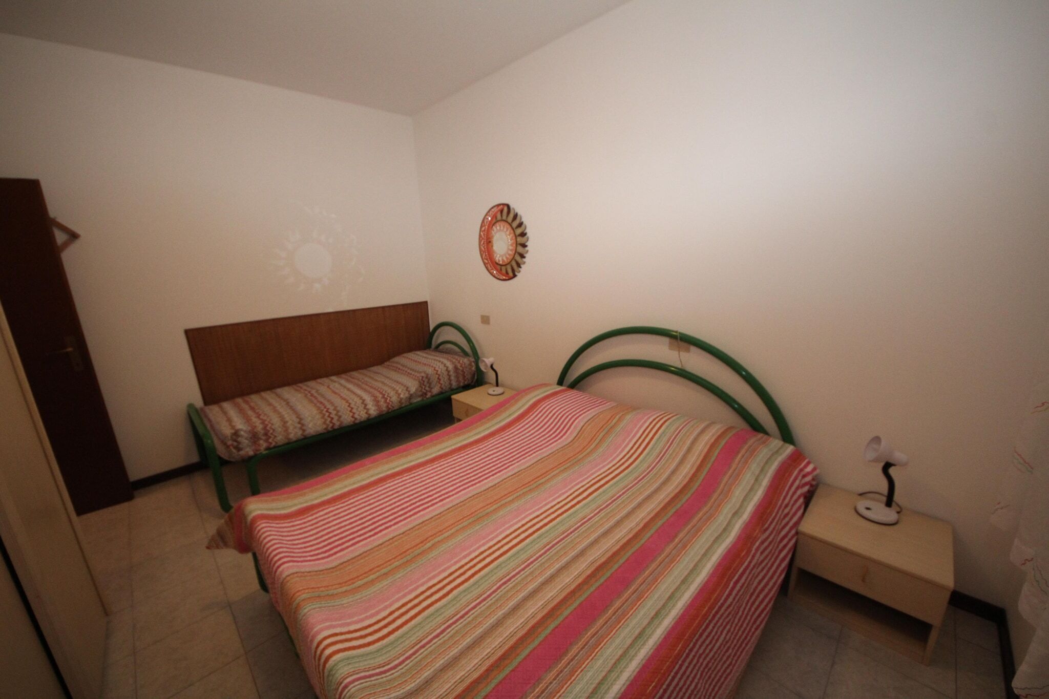 Una camera da letto con un letto, una panca, un comodino e un elemento decorativo a parete.