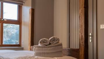 Una habitación de hotel con una cama, un ventanal, un pilar de madera y una puerta.