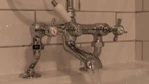 Un baño con grifo de cromo y mandos visibles para agua fría y caliente.