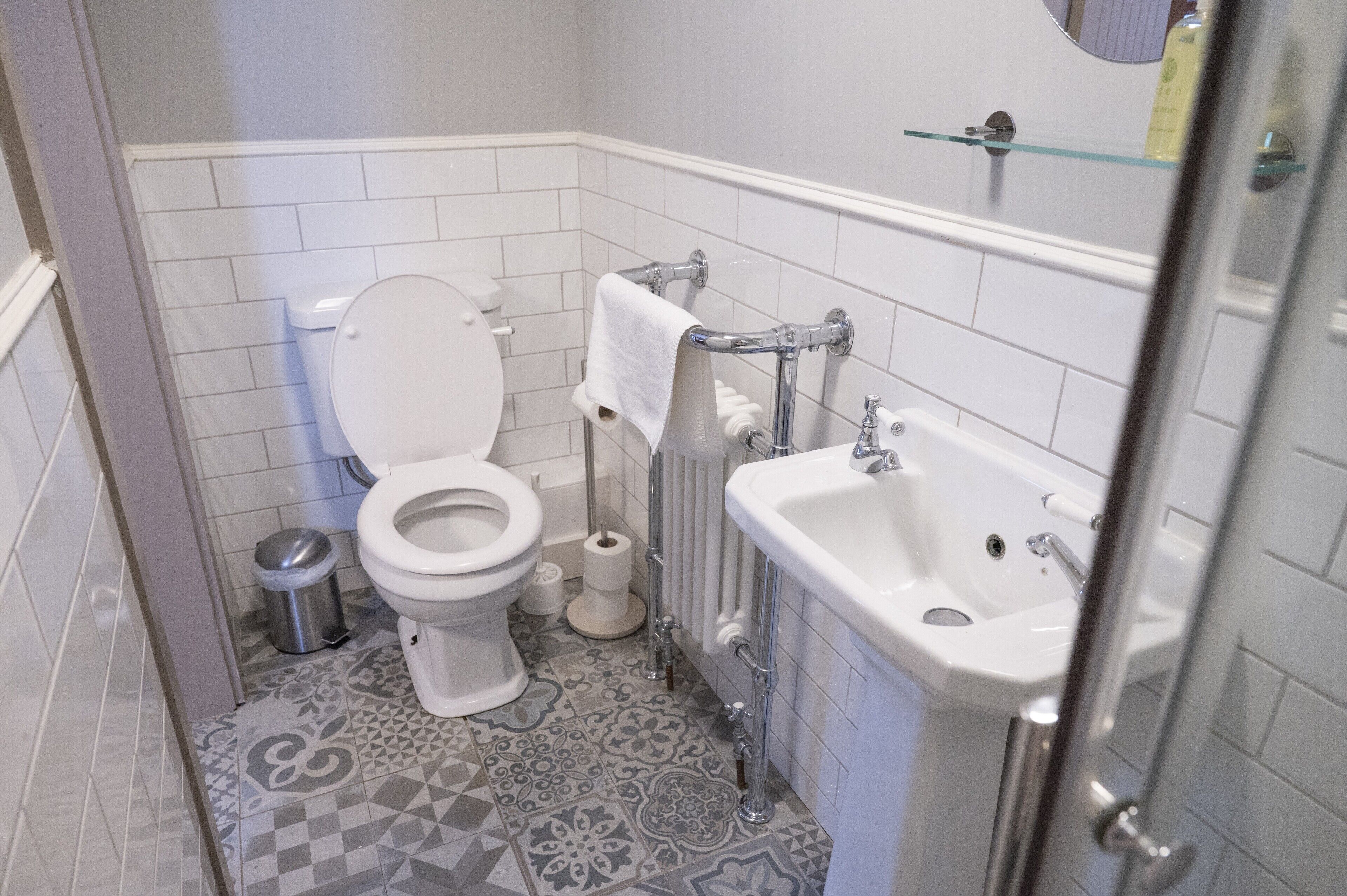 A bathroom with a toilet, sink, and patterned floor tiles.