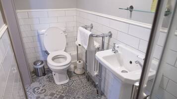 A bathroom with a toilet, sink, and patterned floor tiles.