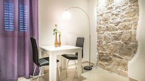 A dining area with a white table, two black chairs, a floor lamp, and a vase with flowers. - Split Oasis Apartments (Split)