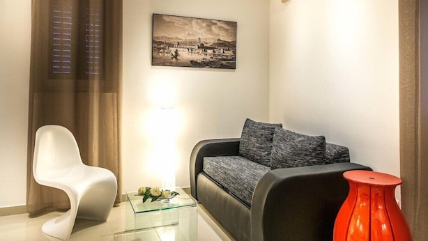 A modern living room with a grey sofa, a white chair, a glass coffee table, and a red vase. - Split Oasis Apartments (Split)