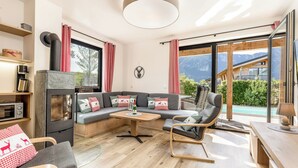 Een moderne woonkamer met een bank, een koffieapparaat, een open haard en uitzicht op de bergen.