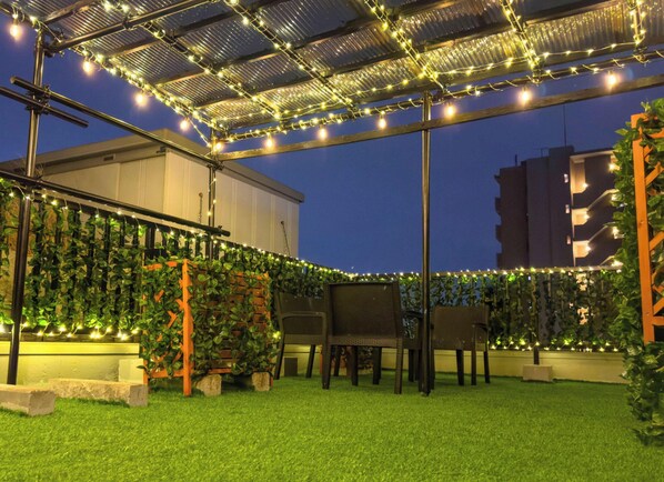 An outdoor patio area with artificial grass, a pergola with string lights, and a seating area with a table and chairs. - 【Rooftop BBQ】Jujo Ginza 3 min 4BR 120㎡丨7/19 IN/OUT (北区)