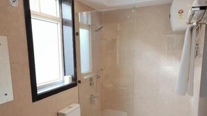 Un baño moderno con ducha acristalada, inodoro blanco y un lavamanos grande.