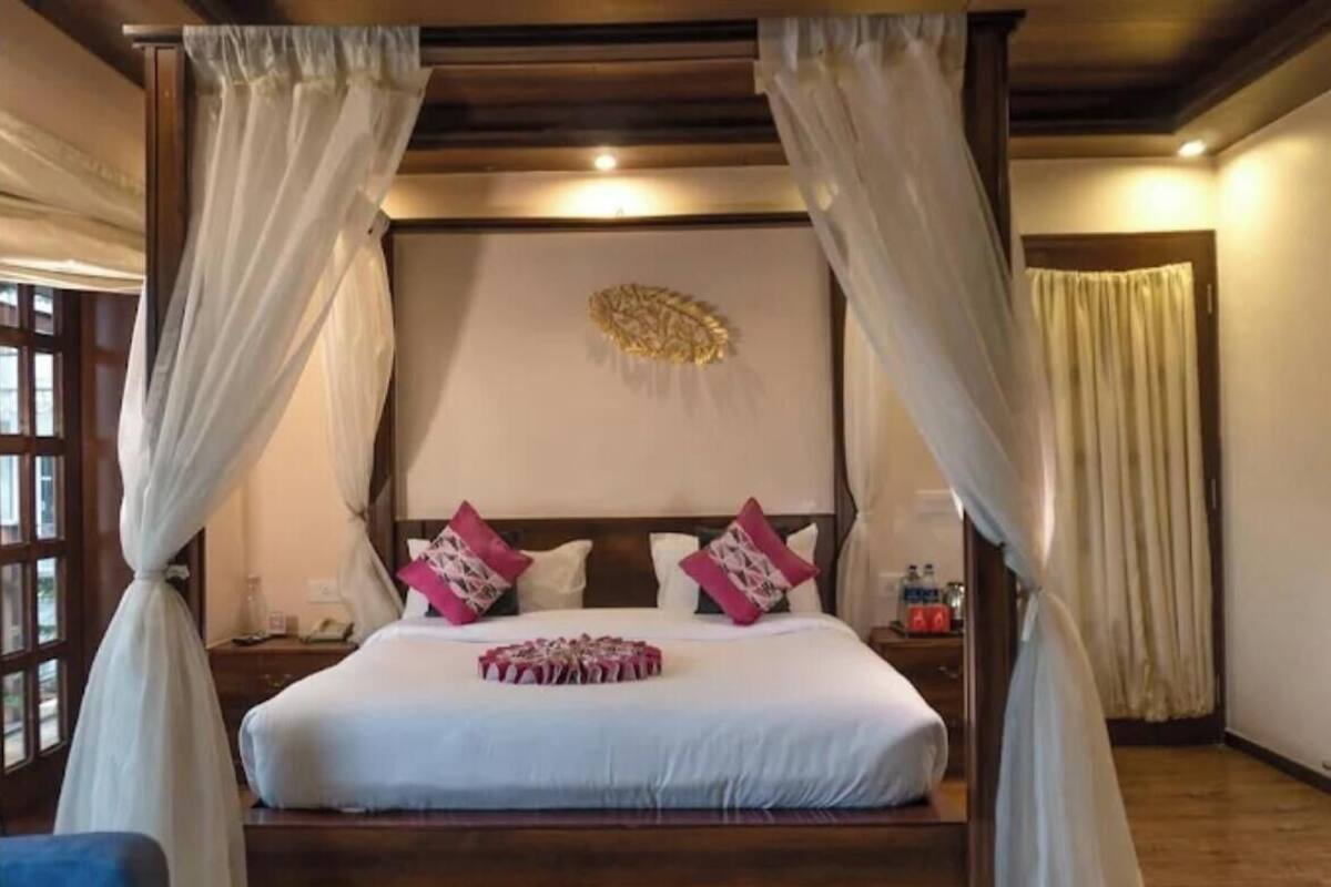 A bedroom with a large bed, white curtains, and a decorative wall piece.