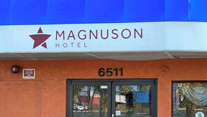 The exterior of the Magnuson Hotel with a blue awning, a fire alarm sign, and the address number 6511. - M-star Bradenton (Bradenton)