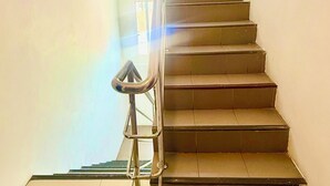 A staircase with metal railings and a view of the outside through a window. - Silver Oaks Guest House (Patong)