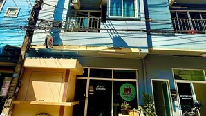 A multi-story building with balconies, air conditioning units, and a storefront with a sign. - Silver Oaks Guest House (Patong)