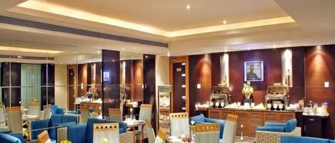 A modern hotel lobby with blue sofas, striped chairs, and a coffee station.